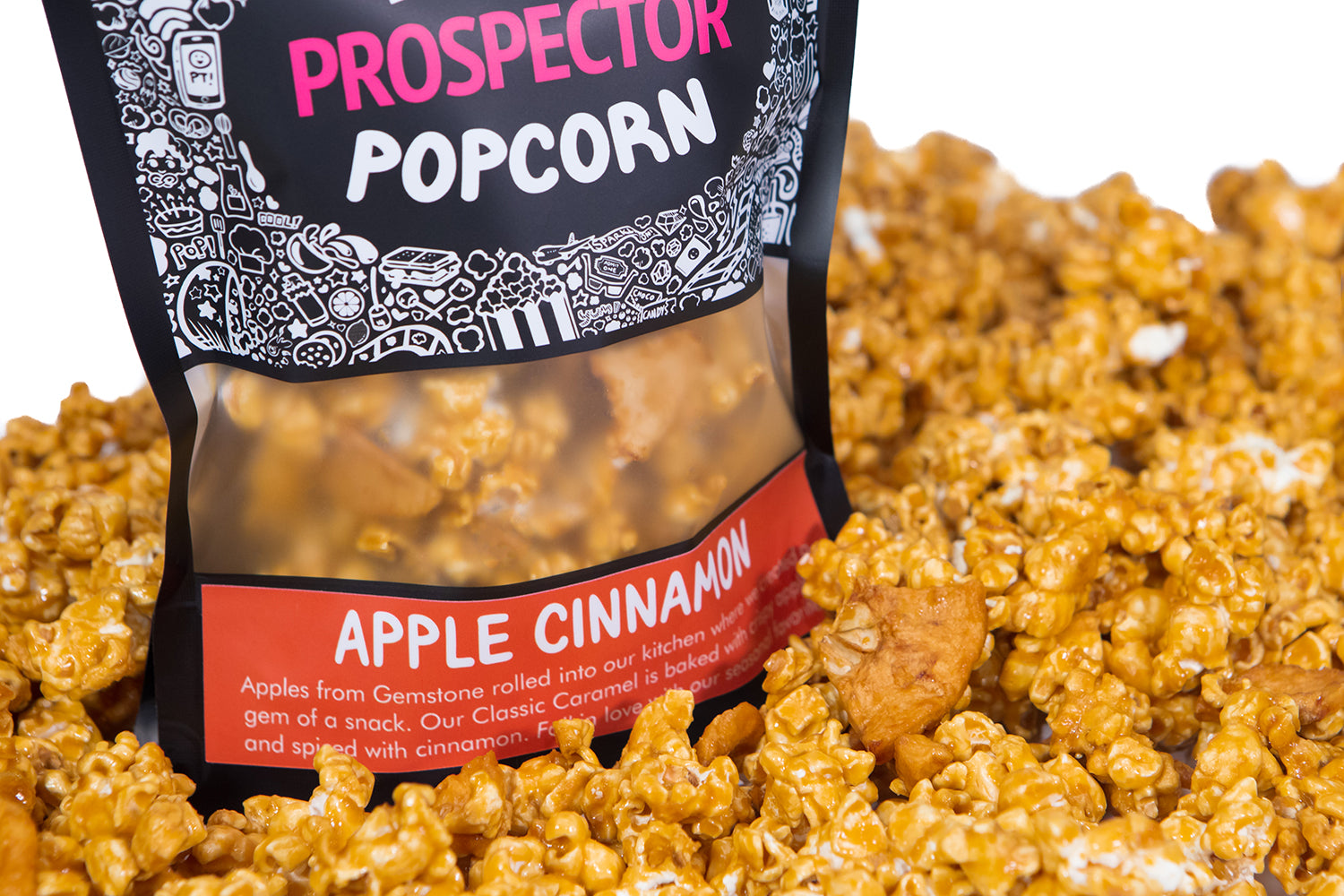 A bag of Apple Cinnamon Prospector gourmet popcorn  sits in a pile of its own popcorn.