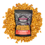 A bag of Apple Cinnamon Prospector gourmet popcorn lays on a bed of its own popcorn