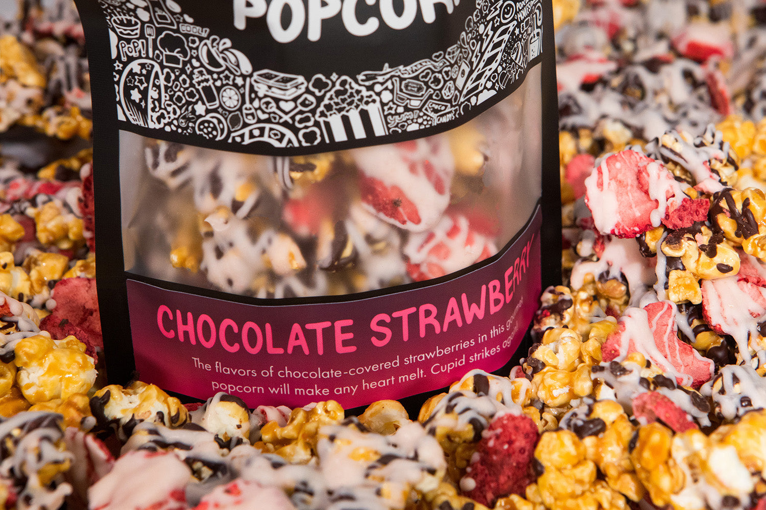 A bag of Chocolate Strawberry gourmet popcorn sits in a pile of its own popcorn