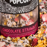 A bag of Chocolate Strawberry gourmet popcorn sits in a pile of its own popcorn