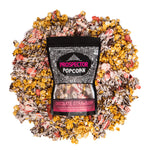 A bag of Chocolate Strawberry gourmet popcorn lays on a pile of its own popcorn.