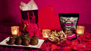 Chocolate covered strawberries are displayed on a plate next to a bowl of Chocolate Strawberry Gourmet Popcorn.
