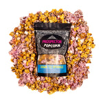 A bag of Down to Sparkle gourmet popcorn lays on a bed of its own popcorn.