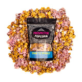 A bag of Down to Sparkle gourmet popcorn lays on a bed of its own popcorn.