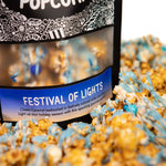 A bag of Festival of Lights gourmet Prospector Popcorn sits in pile of its own popcorn