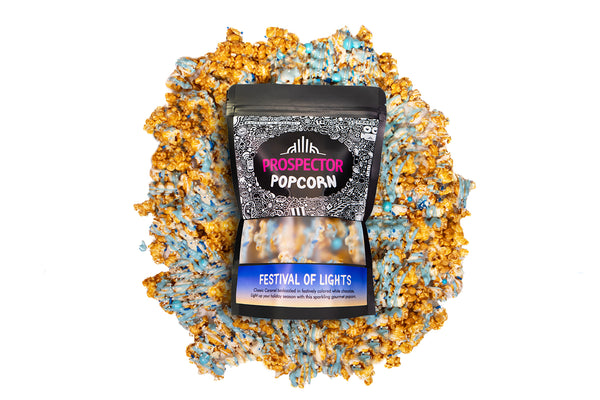 A bag of Festival of Lights gourmet Prospector Popcorn lays on a pile of its own popcorn