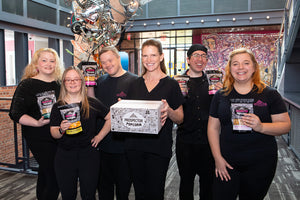 Six Prospects hold up Prospector Popcorn products while smiling in the upper lobby of The Prospector in Ridgefield.