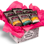 A gourmet popcorn gift box sits on a white background to show off the spicy flavors inside.