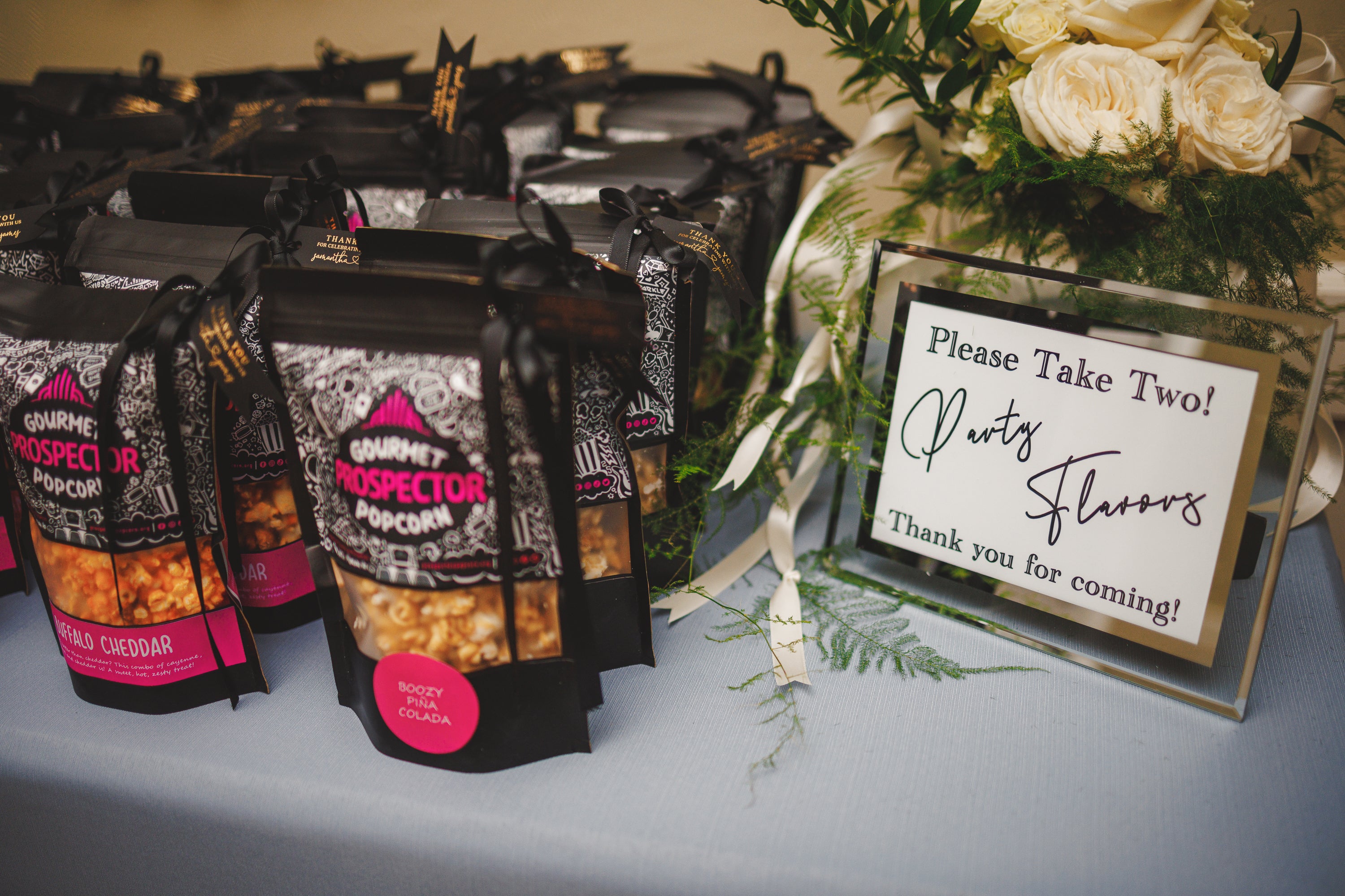 Popcorn Wedding flavors on a table. The sign says Party Favors, Please take two.