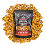 A bag of Pumpkin Spice gourmet popcorn lays on a pile of popcorn on a white background.