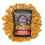 A bag of Pumpkin Spice gourmet popcorn lays on a pile of popcorn on a white background.