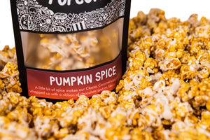 A bag of Pumpkin Spice gourmet popcorn sits in a pile of its own popcorn