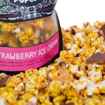 A bag of Strawberry Ice Cream gourmet popcorn sits in a pile of its own popcorn