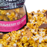 A bag of Strawberry Ice Cream gourmet popcorn sits in a pile of its own popcorn