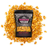 A bag of Sweet and Spicy gourmet popcorn lays on a pile of its popcorn