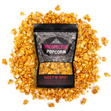 A bag of Sweet and Spicy gourmet popcorn lays on a pile of its popcorn