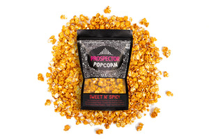 A bag of Sweet and Spicy gourmet popcorn lays on a pile of its popcorn