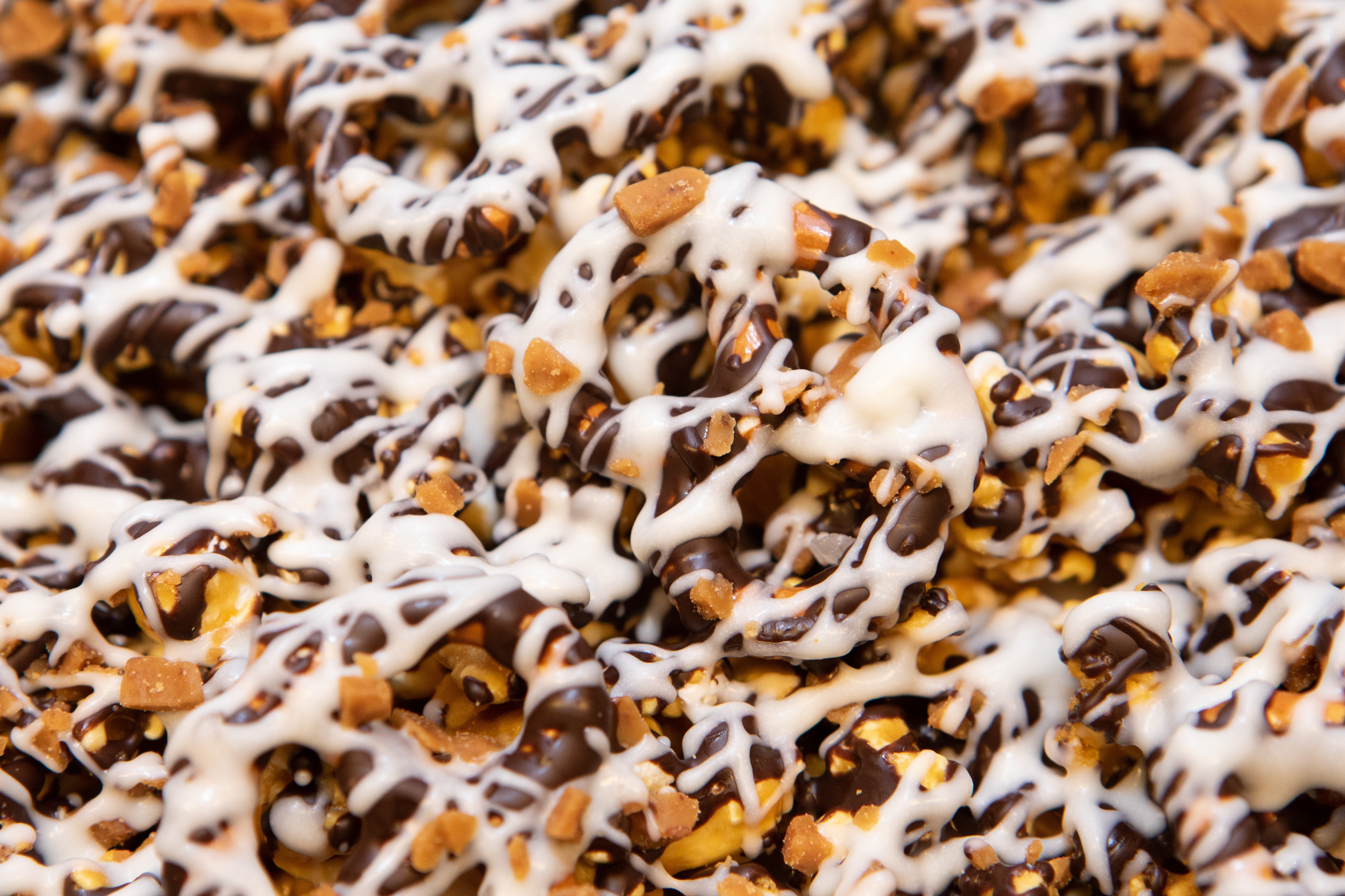 Close up of white chocolate drizzle on chocolate toffee popcorn 