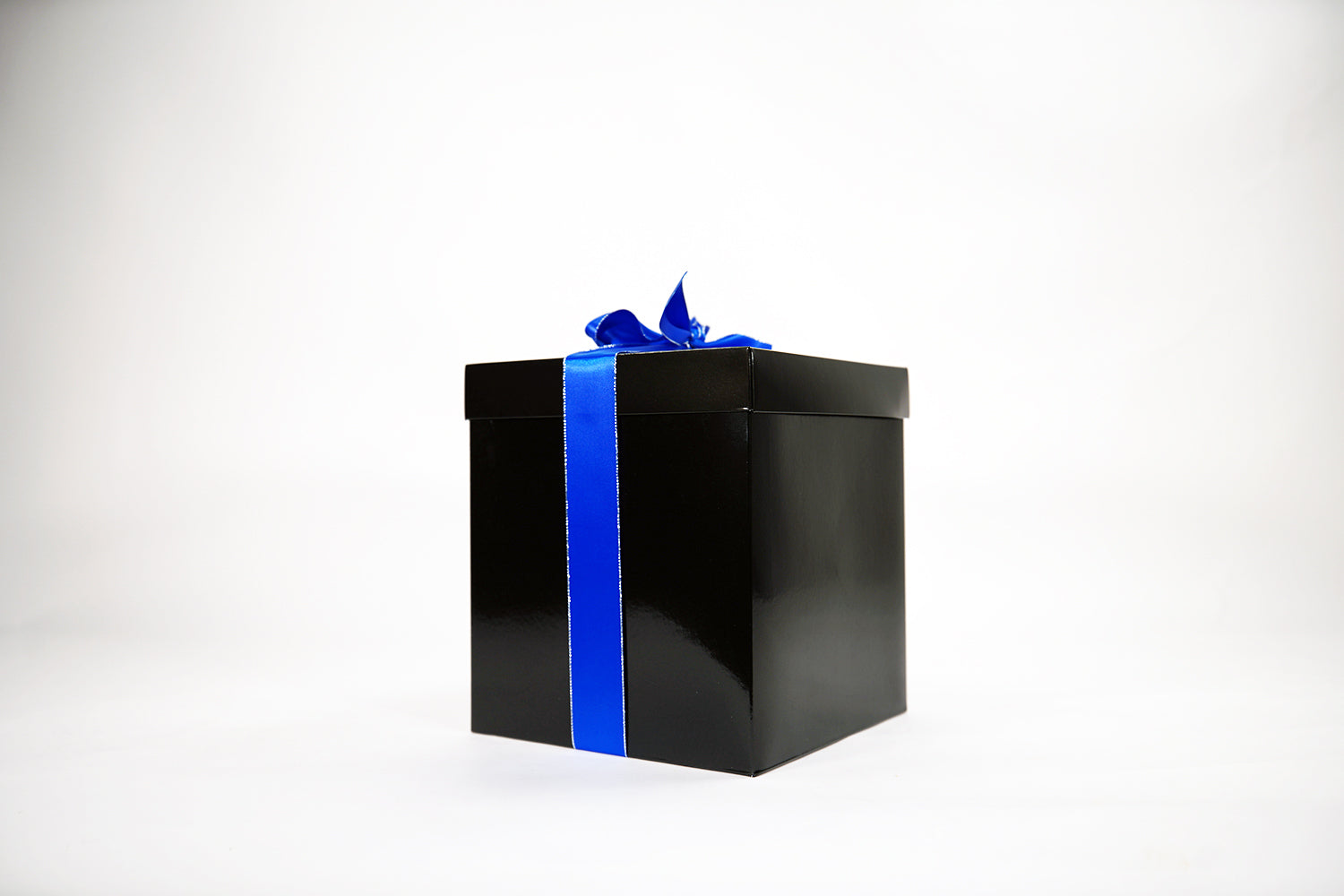 A shiny black gift box with a bright blue ribbon bow on top sits on a plain white background.