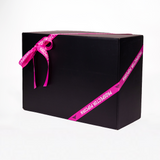 A large black gift box wrapped with a purple ribbon that has the words "Prospector Popcorn" printed on it. The box is set against a plain white background.