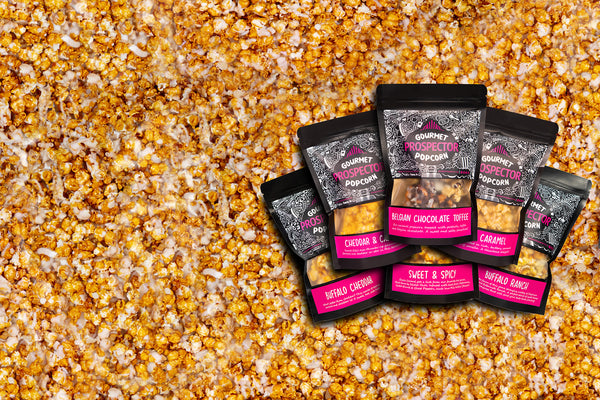 7 assorted gourmet popcorn flavors lay on a background of popcorn